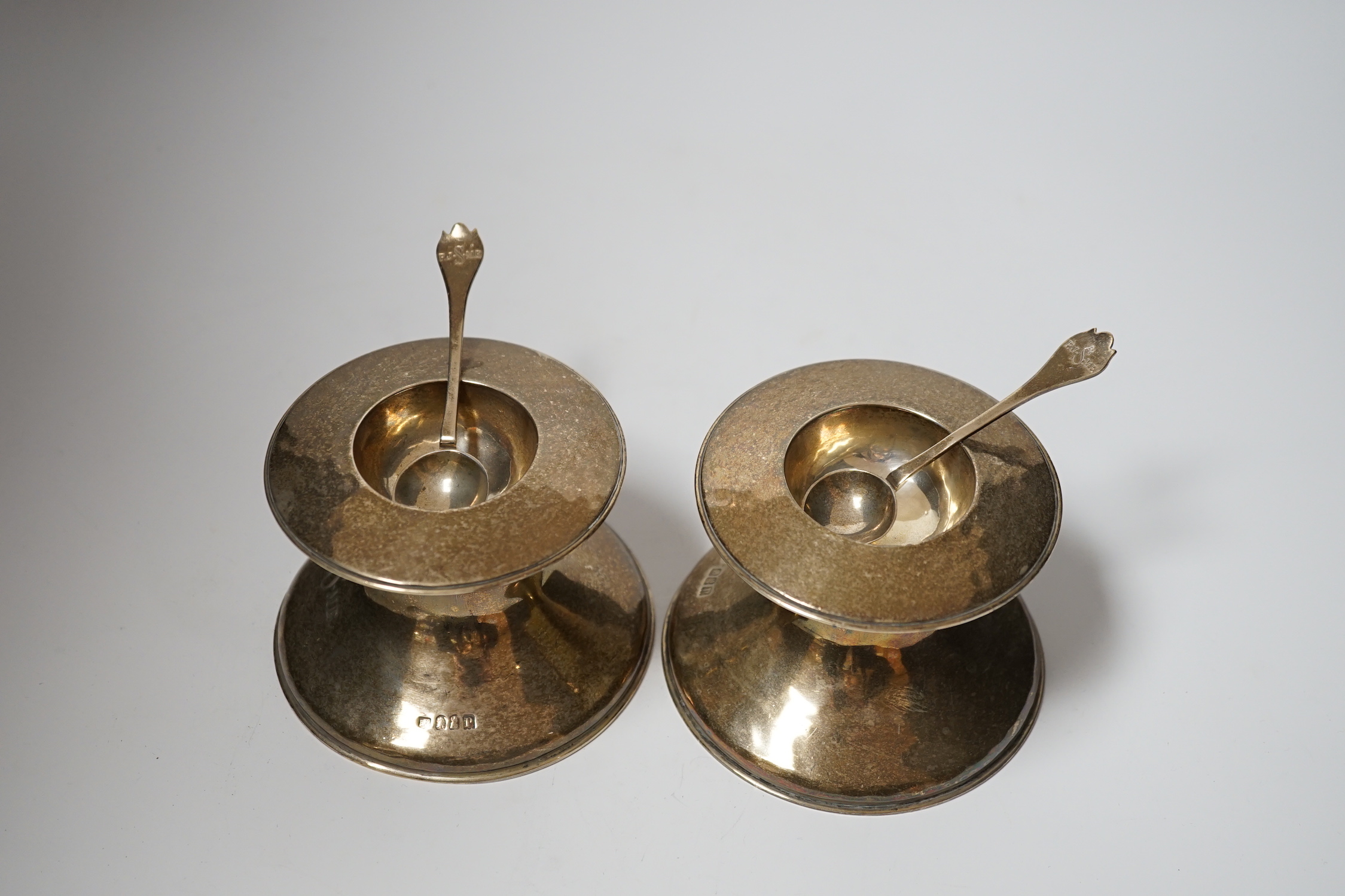 A pair of George V Britannia standard silver salts, of waisted form, with two matching spoons, Lambert & Co, London, 1910, height 79mm, 22oz.